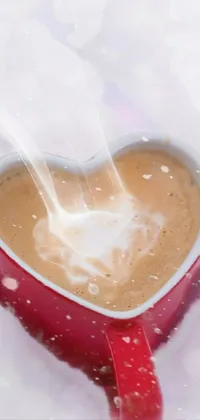This phone live wallpaper features a heart-shaped cup of coffee set in a wintry wonderland