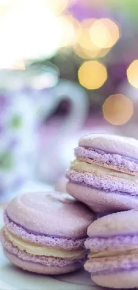 This phone live wallpaper features a stunning scene of a white plate topped with an array of delightful purple macarons next to a freshly brewed cup of coffee