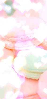 This live wallpaper showcases a white plate with colorful French macarons and a pink rose on top against a pastel background with shades of pink and blue