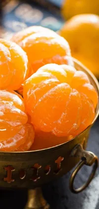 This live wallpaper features a close-up of a bowl filled with juicy oranges resting on a wooden tabletop