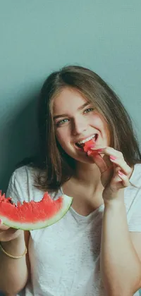This live phone wallpaper features a smiling, young woman enjoying a refreshing slice of watermelon