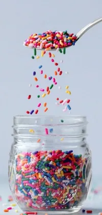 This live phone wallpaper is a fun and colorful graphic featuring sprinkles in a jar and on a spoon, as well as a floating picture