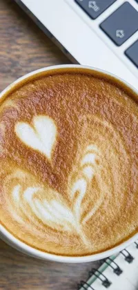 This phone live wallpaper showcases a cup of coffee on a wooden table with intricate latte art and a heart-shaped face