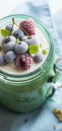 This phone live wallpaper depicts a cup of yogurt topped with blueberries and raspberries against a pastel green background