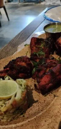 Looking for a visually appealing phone live wallpaper? Check out an exquisite view of a wooden plate of Indian-style grilled chicken that's guaranteed to stimulate your senses! The photo captures a close-up shot of the dish that's artfully arranged to perfection with an artistic touch of Hurufiyya flavor