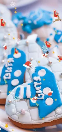Add a sweet touch to your phone with this live wallpaper featuring a white plate filled with mouth-watering cupcakes covered in colorful frosting and embellished with blue ornaments and tempting cookies