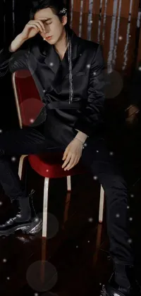 This striking phone live wallpaper features a man in a black baroque-style outfit sitting on a bright red chair