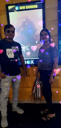 This mesmerizing live wallpaper for your phone features a stunning scene of a man and a woman standing together in front of a massive screen