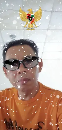 This phone live wallpaper features a man in an orange shirt taking a selfie while wearing modern glasses