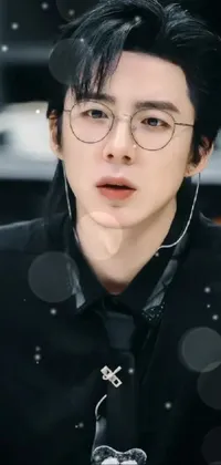 This stunning phone live wallpaper features a person wearing glasses and a tie, dressed in black, with long black hair blowing in the wind