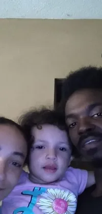 This live wallpaper features a man and a woman holding their smiling baby in a fun "afro samurai" selfie pose