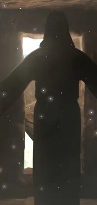 This stunning live phone wallpaper displays a person standing in front of a window, with a cosmic entity of stars in the distance