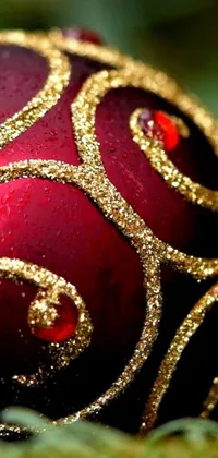 This lively Christmas phone wallpaper showcases a close-up view of a vibrant red and gold ornament, highlighted by an intricate scrollwork pattern and sparkling glitter accents