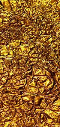 This stunning phone live wallpaper showcases a bright and detailed photo of a piece of gold foil, against the backdrop of a rich and vibrant lava texture