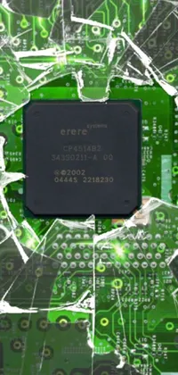This phone live wallpaper showcases a broken computer chip resting on a green circuit board, set against a backdrop of a shattered wall