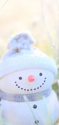 A cozy and charming snowman sits on green grass in this digital art phone wallpaper