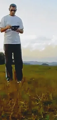This live wallpaper portrays a man standing on top of a green field, exercising with his arms raised high