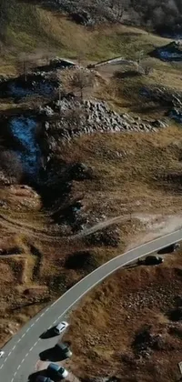 This phone live wallpaper features a picturesque drive, with two cars navigating a winding road