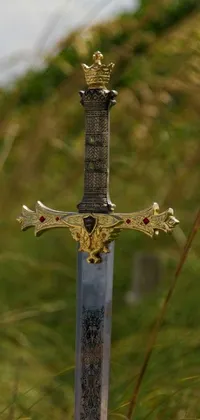 This phone live wallpaper features a sword with a cross symbol lying in the grass