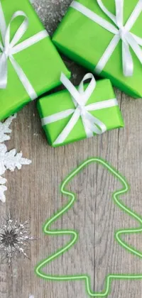 This phone wallpaper showcases a vibrant green gift box sitting atop a wooden table