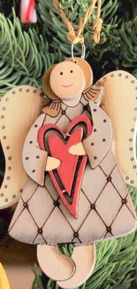 This phone live wallpaper features a wooden angel ornament hanging from a Christmas tree and holding a heart