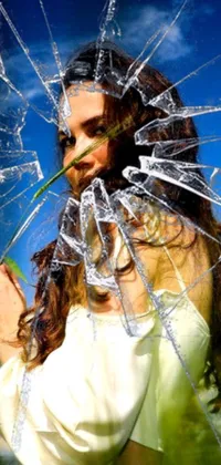 This phone live wallpaper showcases a stunning image of a woman holding a flower behind a glass window that has shattered, creating an intricate pattern of broken glass