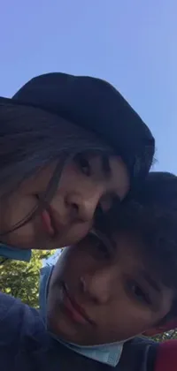 This phone live wallpaper features a couple taking a selfie in the park
