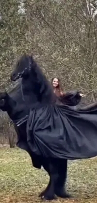 This live phone wallpaper showcases a stunning image of a woman riding on the back of a black horse, wearing a cloak from neck to ankles, and a dress made of flowing vines
