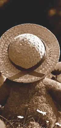 Enjoy the serene sight of a fluffy teddy bear wearing a straw hat sitting atop a bed of bright daisies in this sepia-toned phone live wallpaper
