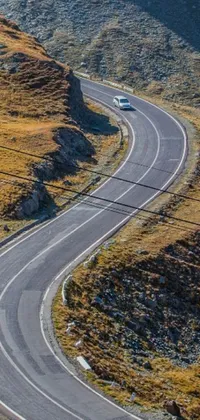 This phone live wallpaper showcases a thrilling image of a car driving down a winding mountain road