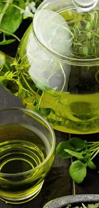 This phone live wallpaper features a calming scene of green tea in a teapot and cup, surrounded by aquatic plants and glass bottles with small plants