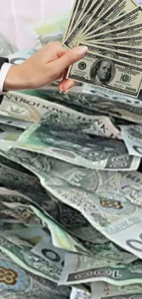 This live phone wallpaper depicts an eye-catching image of a person dressed in a suit holding a fan of cash, with piles of money visible in the background