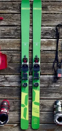This lively live phone wallpaper depicts an array of skis on a wooden floor, accessorized with ski straps, patent leather bindings, and snow goggles