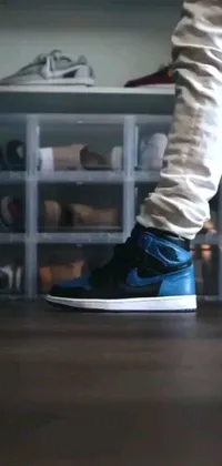 This phone live wallpaper features a wooden floor with a person standing on it wearing the iconic Air Jordan 1, Blue Shadow sneakers