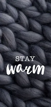 This mobile wallpaper features a textured knitted blanket close-up with the words "stay warm" in a minimalist font
