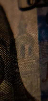 This phone live wallpaper showcases a striking close-up of a person's face on a dollar bill
