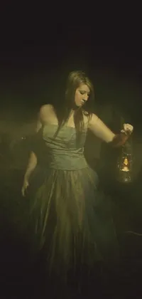 This live wallpaper depicts a woman in a green dress holding a lantern, emitting a soft glow