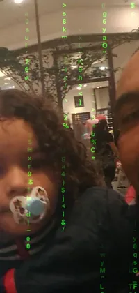 This live wallpaper depicts a delightful moment, captured in a mall, featuring a man photographing a little girl holding a pacifier