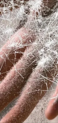 This live phone wallpaper features a stunning close-up of a hand covered in fine white fairy dust