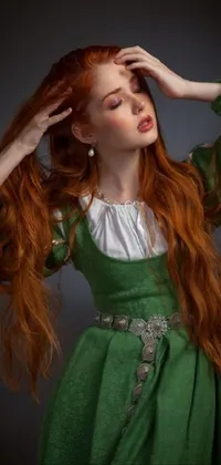 This phone live wallpaper showcases a stunning woman with long red hair wearing a green dress inspired by the Renaissance era and Russian clothing