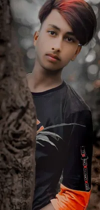 This mobile live wallpaper displays a close-up portrait of a young boy, dressed in sportswear and standing next to a tree