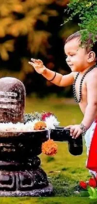 This phone live wallpaper features a charming scene of a child standing beside a serene water fountain