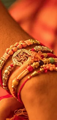 This live phone wallpaper features a stunning close-up of a bohemian-inspired arm with multiple red and orange bracelets