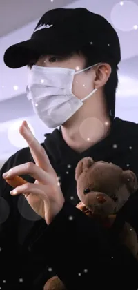 Looking for a stylish phone live wallpaper? Check out this stunning image that features a masked man in black clothing, holding a cute teddy bear