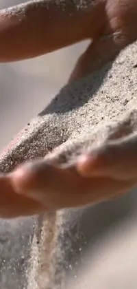 Looking for a serene and calming live wallpaper for your phone? This design features a close-up of a hand holding sand, captured in ultra high-quality for stunning clarity