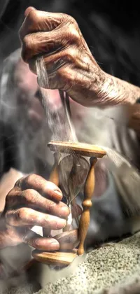 This captivating phone live wallpaper depicts a hyperrealistic close-up of an hourglass being held by an older seemingly hardworking man