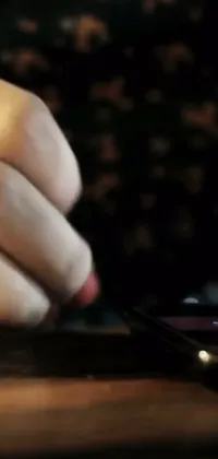 This phone live wallpaper features an up-close image of a cell phone user's hand on a table, taking a moment to check their device