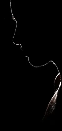 This phone live wallpaper is a captivating minimalistic depiction of a person's face in the dark