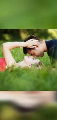 This phone live wallpaper showcases a serene and romantic scene of a man and woman lying on a green grass field