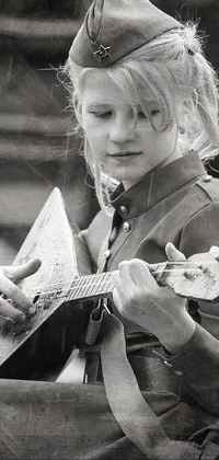 This live wallpaper for your phone showcases an evocative black and white photograph of a young girl playing a guitar, dressed in a soldier uniform